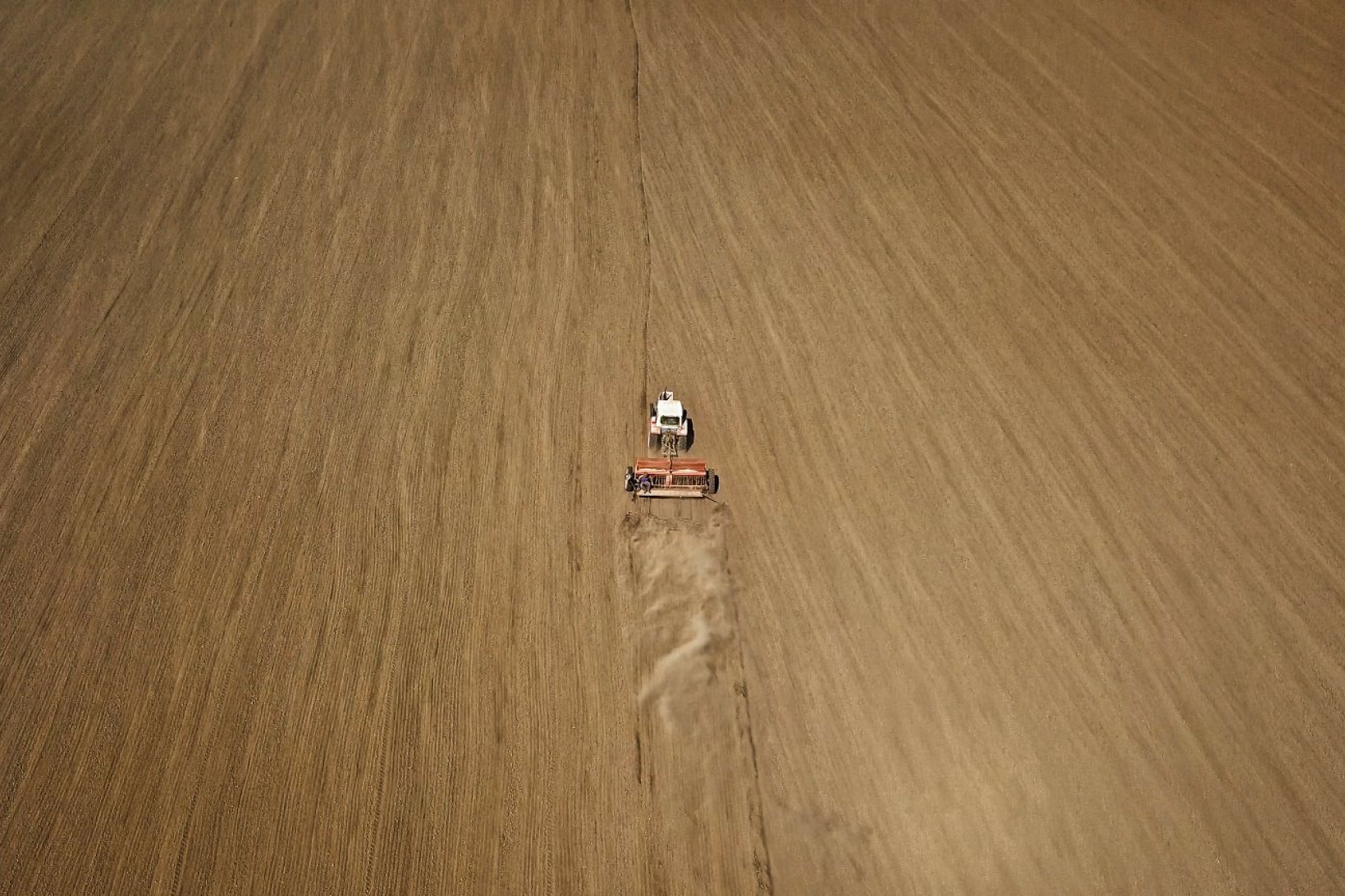 Luftfoto af en traktor, der kører over en hvedemark